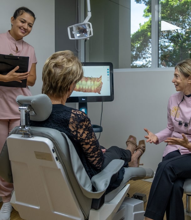 Dr. Thanos and team talking with a smiling patient at B Well Dental Studio